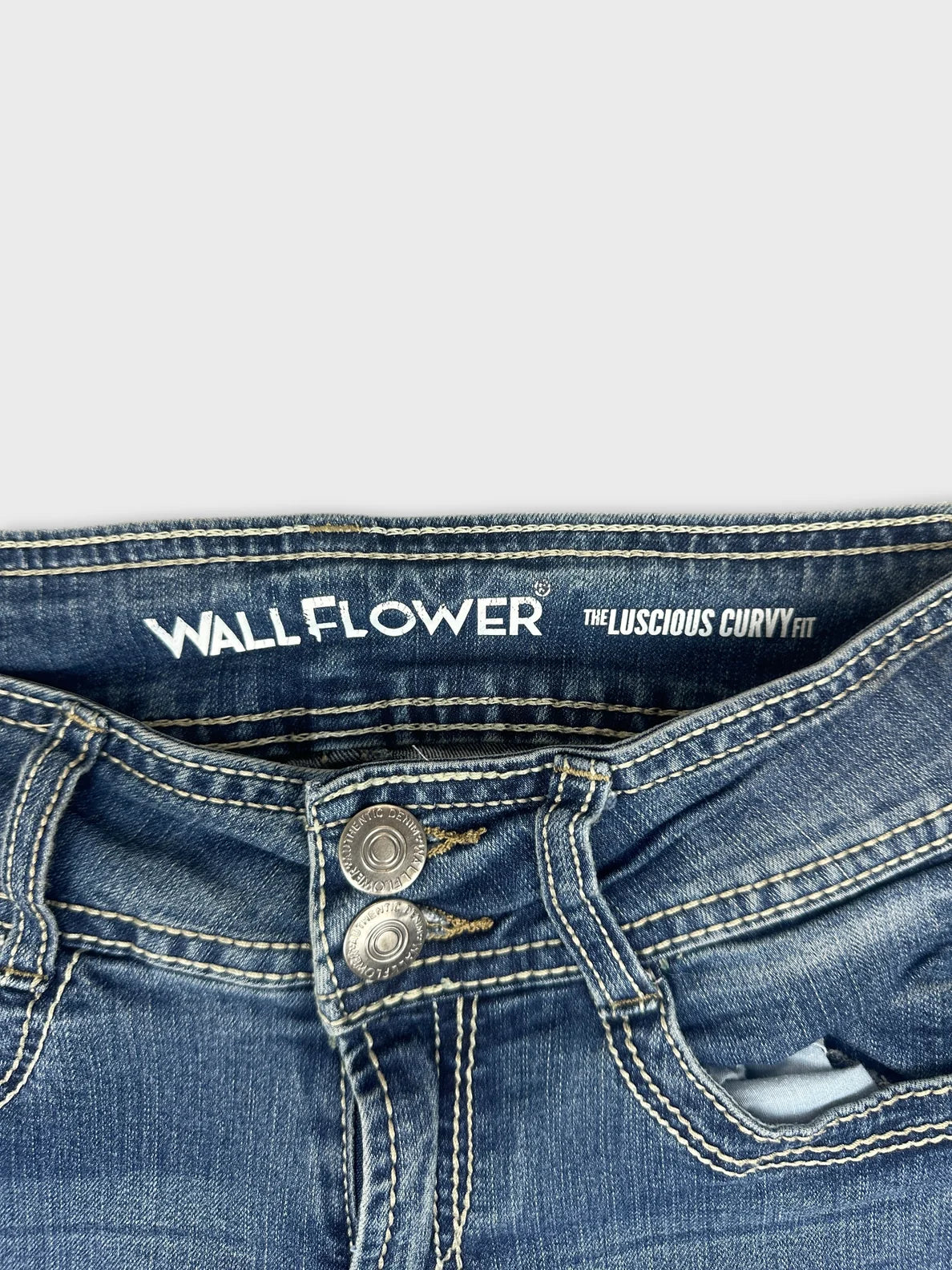 Detail view of women denim jeans with blue color and two-button closure.