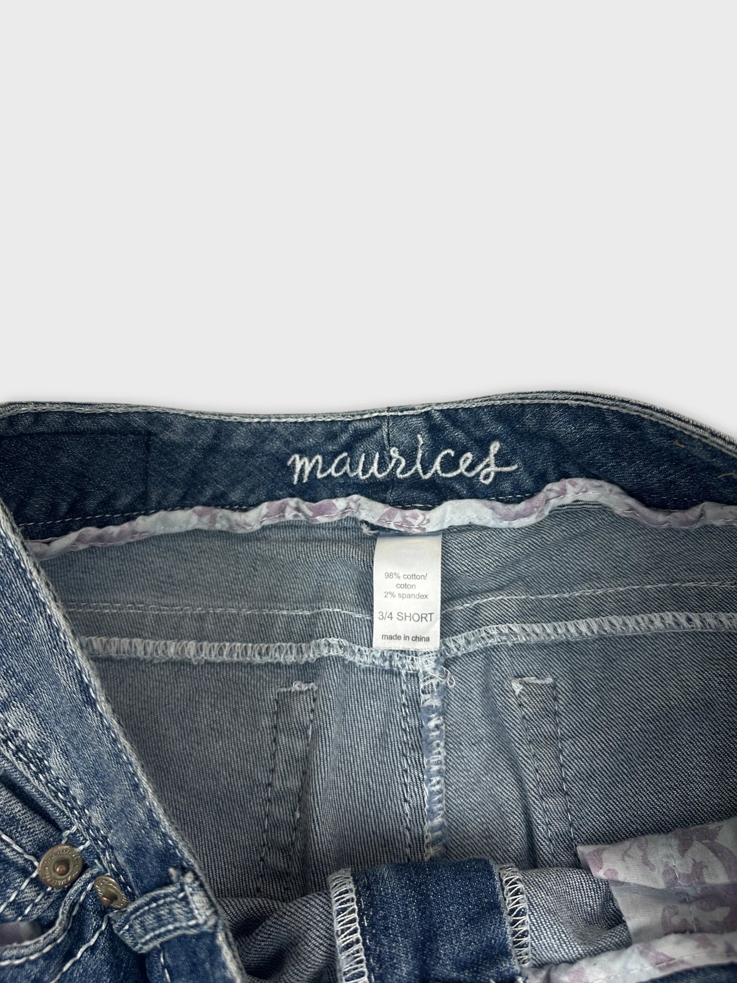Detail view of women denim jeans with a blue color and floral trim.