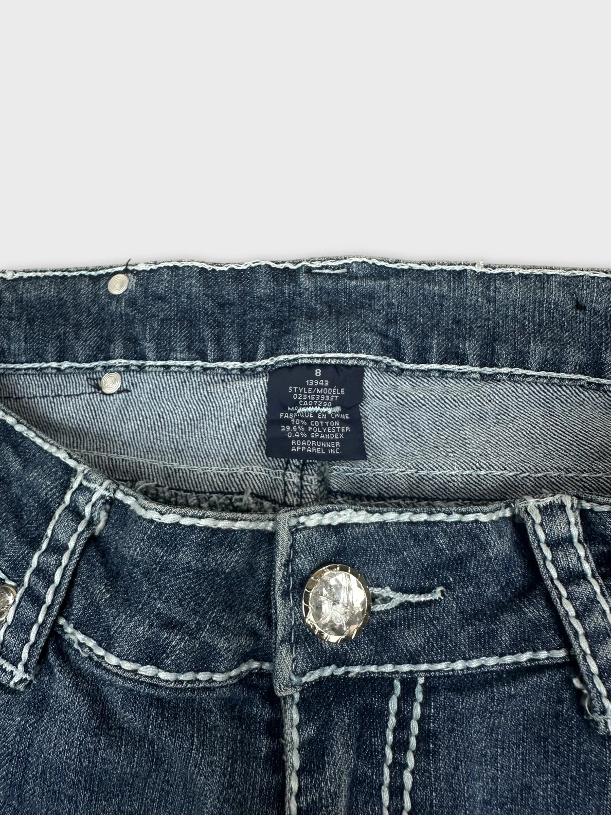Detail view of women denim jeans in dark blue with decorative button
