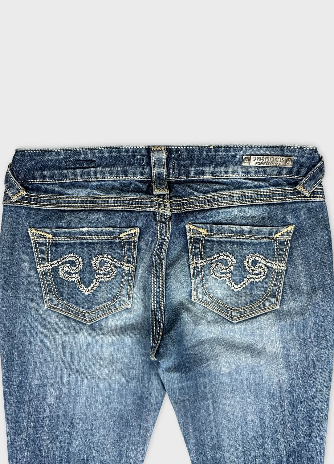 Detail view of women denim jeans in light blue with decorative back pocket embroidery.