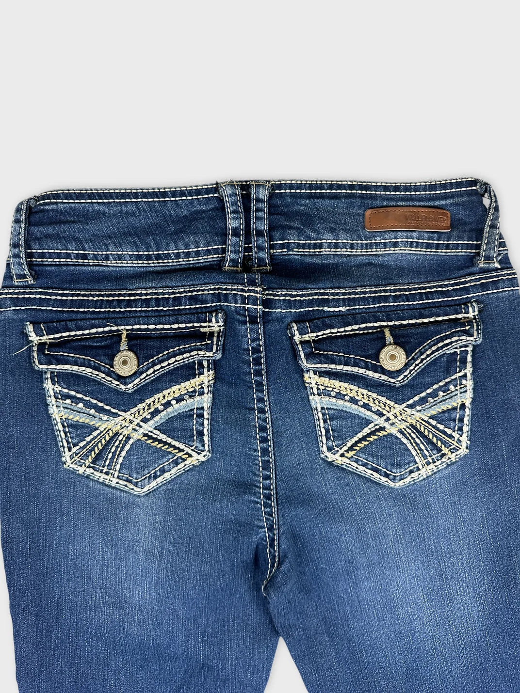 Women denim jeans in dark blue with intricate back pocket detail view.