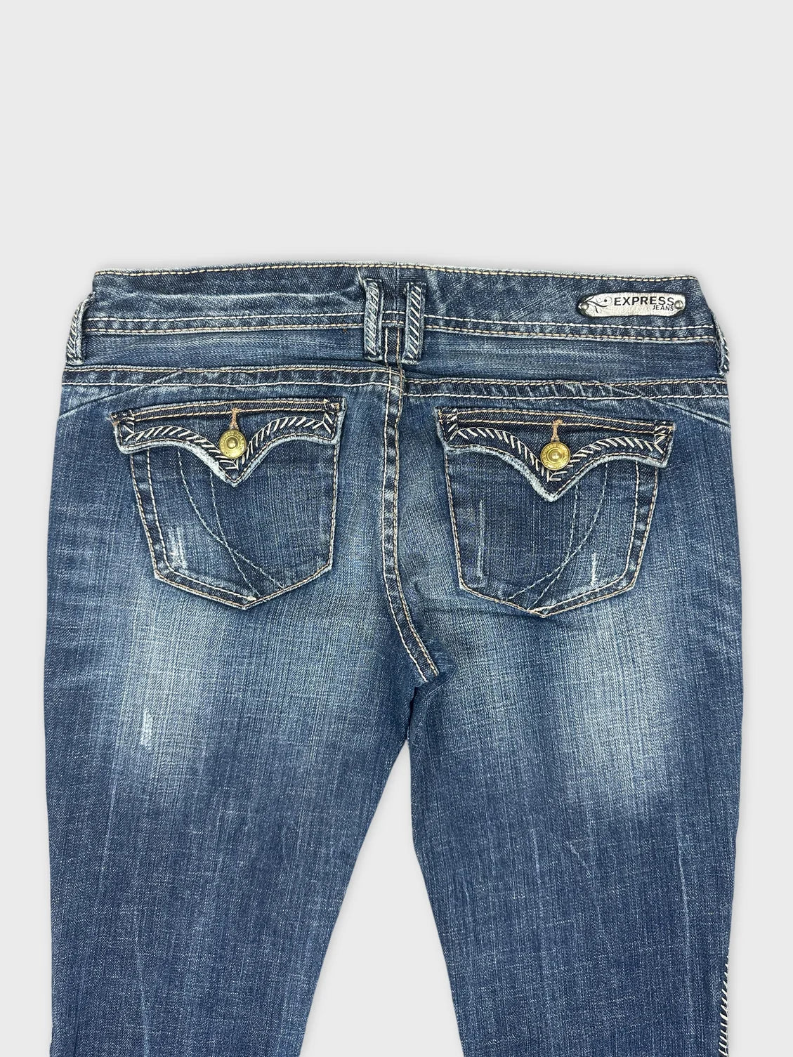 Detail view of women denim jeans showcasing blue color and unique pocket design.