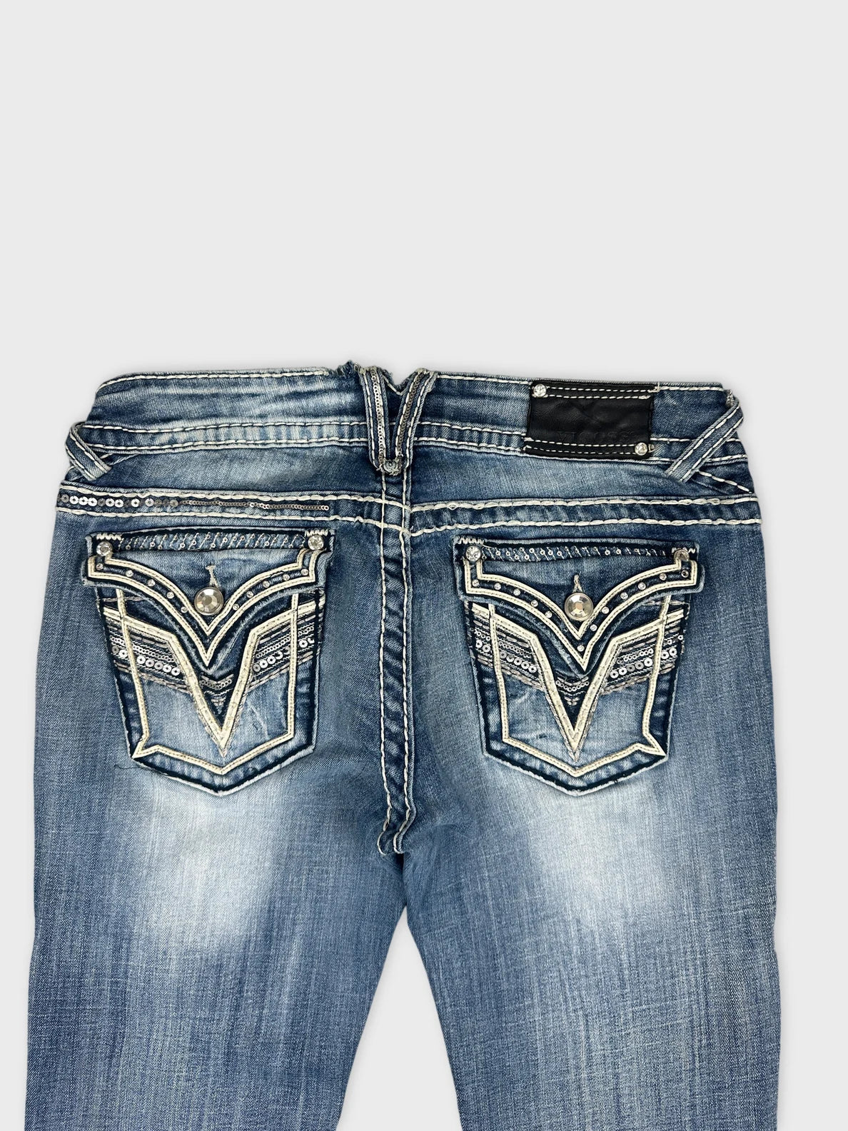 Detail view of women denim jeans featuring intricate back pocket embroidery.