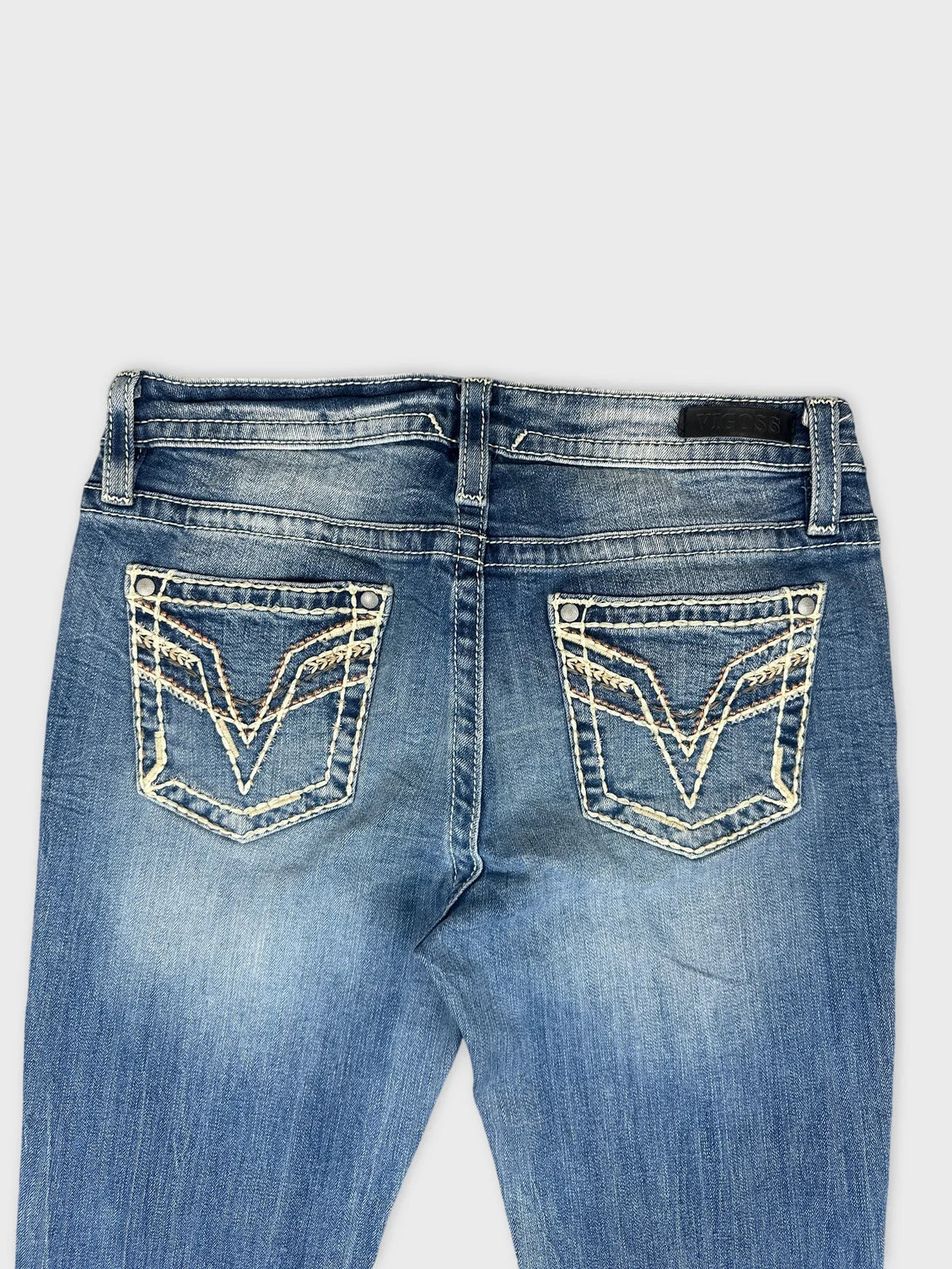 Detail view of women denim jeans in light blue with decorative back pockets.