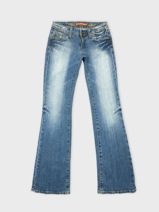 Front view of blue denim jeans with a flared leg design and distressed detailing.