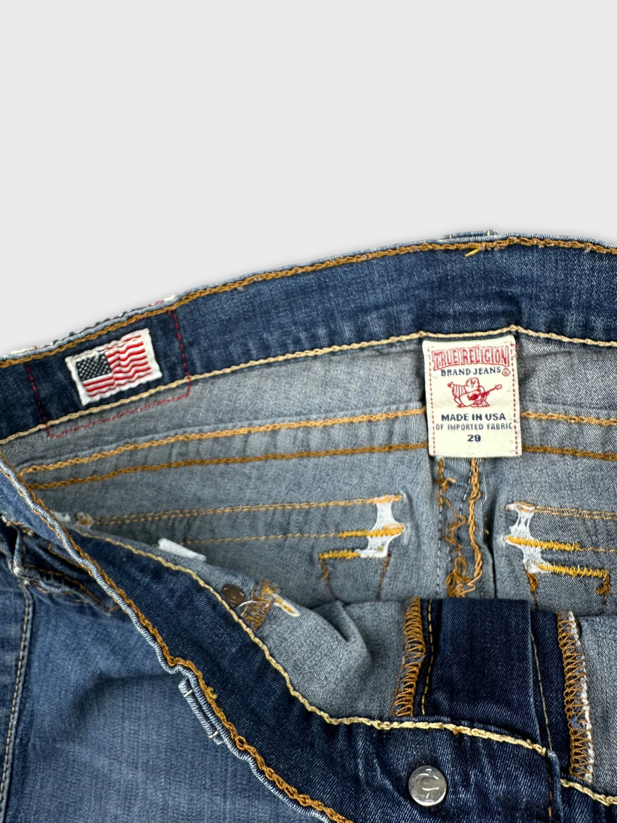 Detail view of a women's denim shirt featuring blue color and orange stitching.