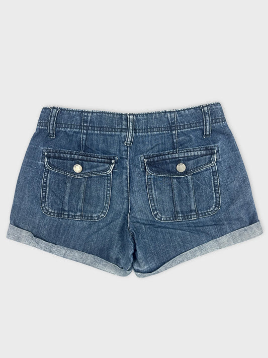 Back view of blue denim shorts with pocket detailing and rolled hems.