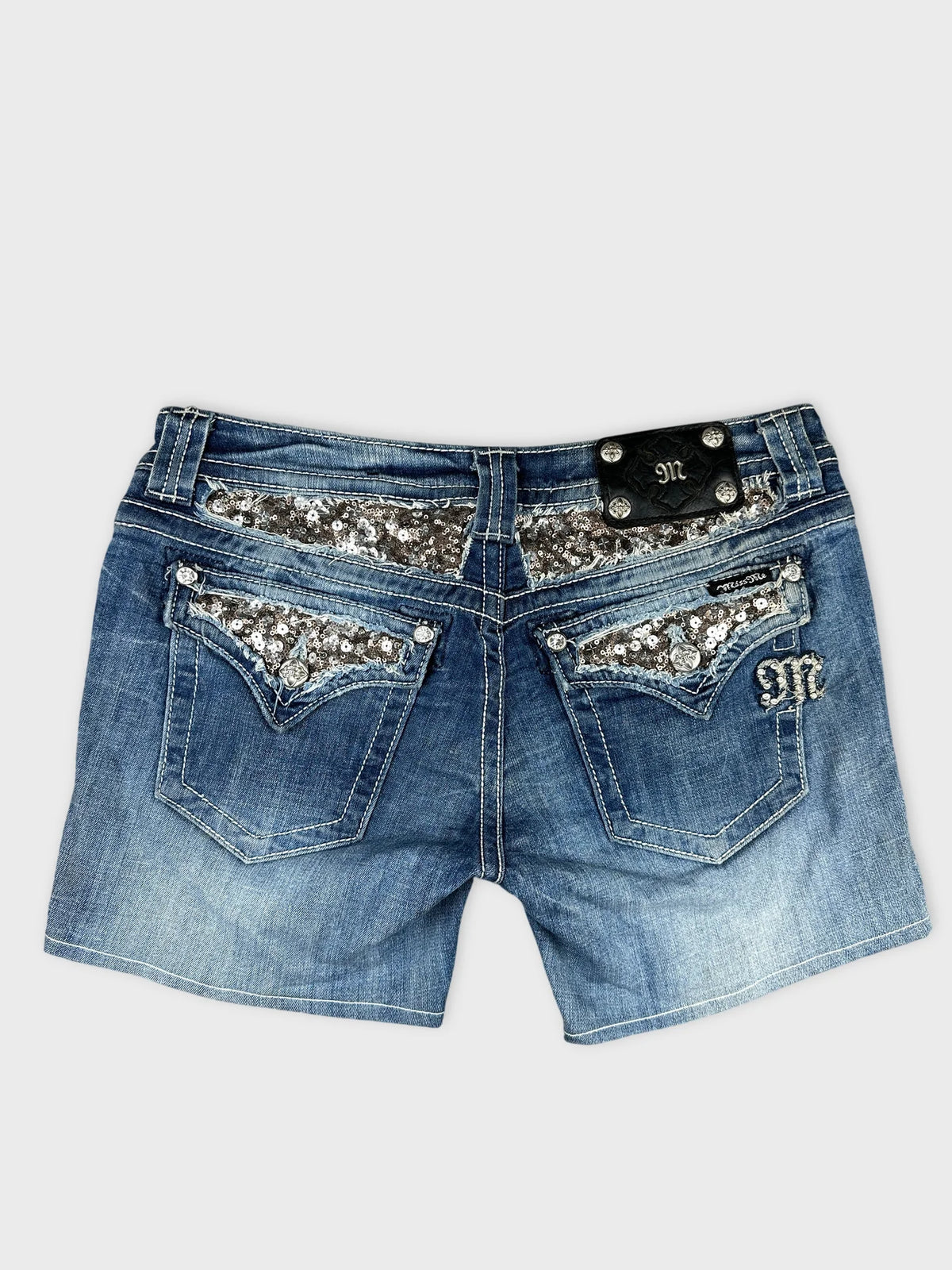 Back view of denim shorts with silver sequin detail on pockets.