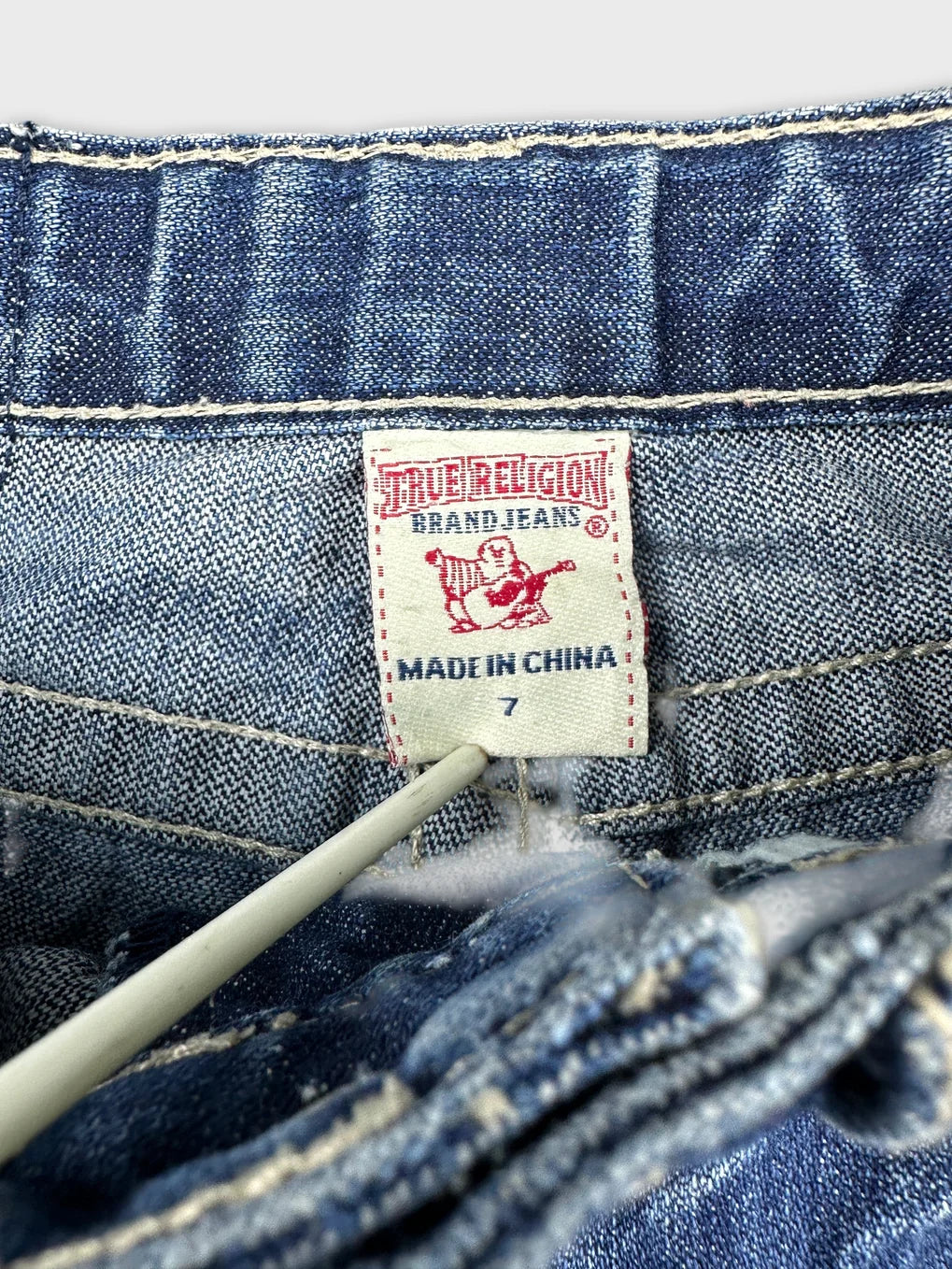 Detail view of blue denim shorts showing the brand tag inside.