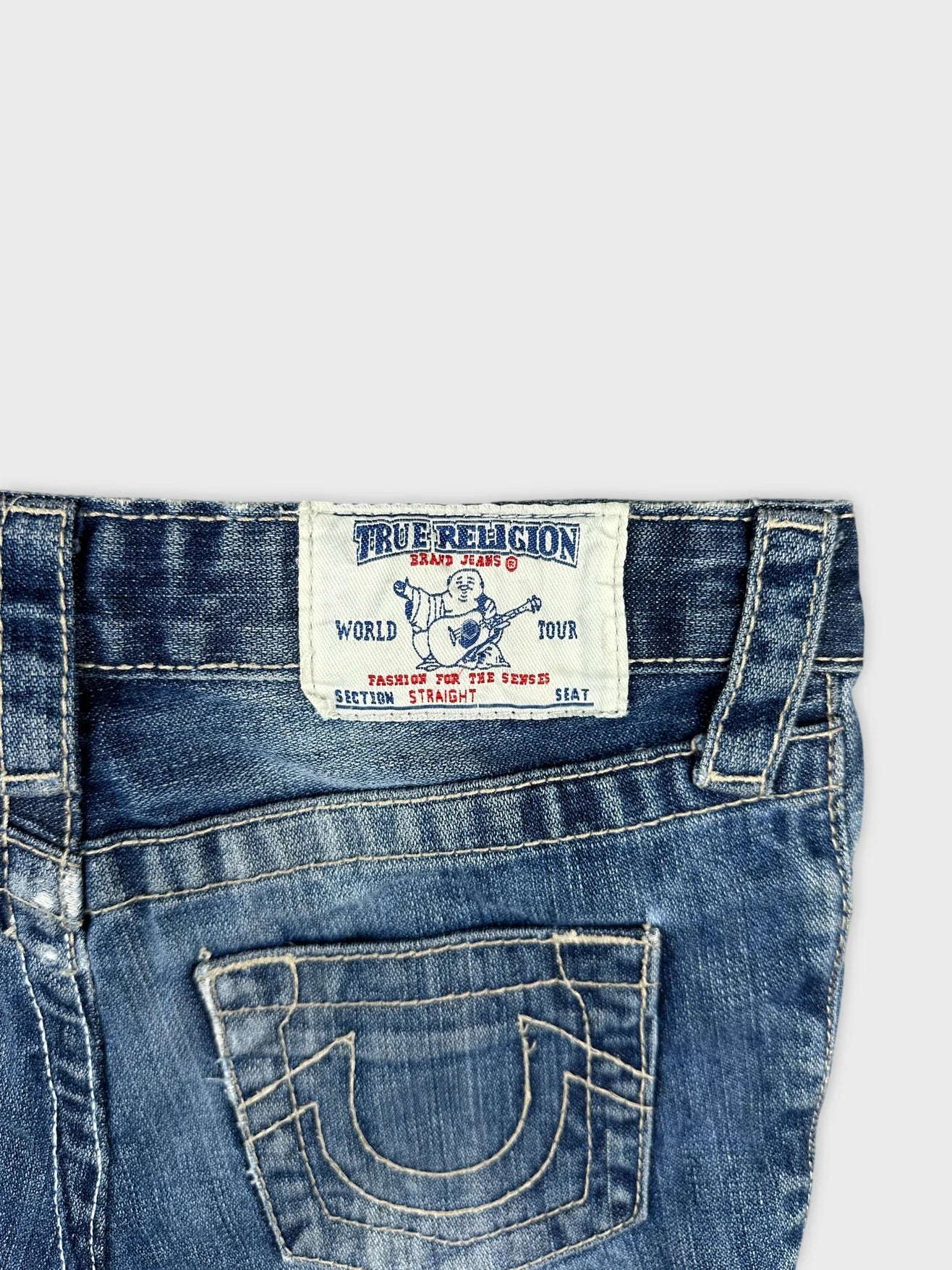Detail view of women denim shorts in dark blue with logo patch.