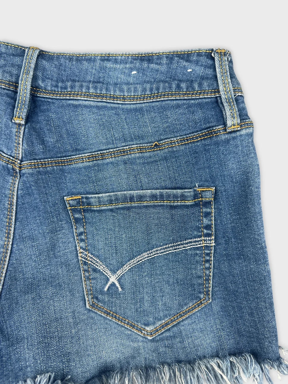 Detail view of blue denim shorts featuring exposed pocket stitching.