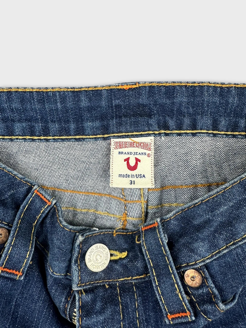 Detail view of women denim shorts featuring blue fabric and orange stitching.