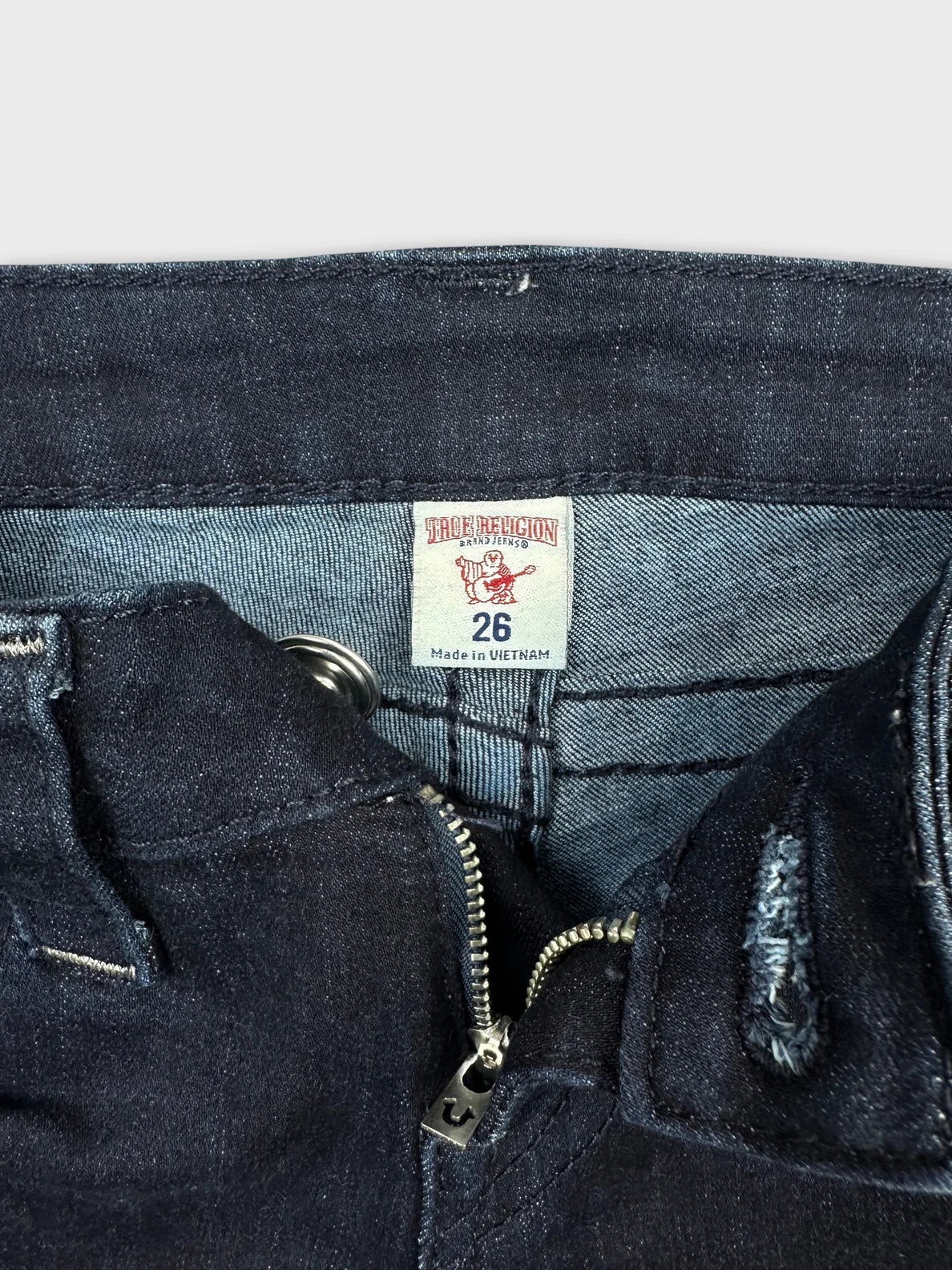 Detail view of dark denim shorts showing zipper and interior stitching.