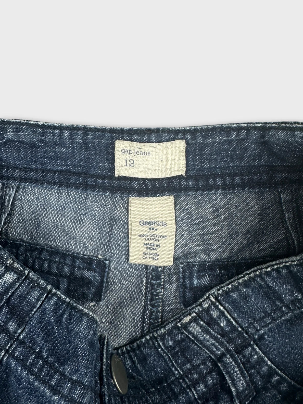 Detail view of women denim shorts in dark blue with a button closure.