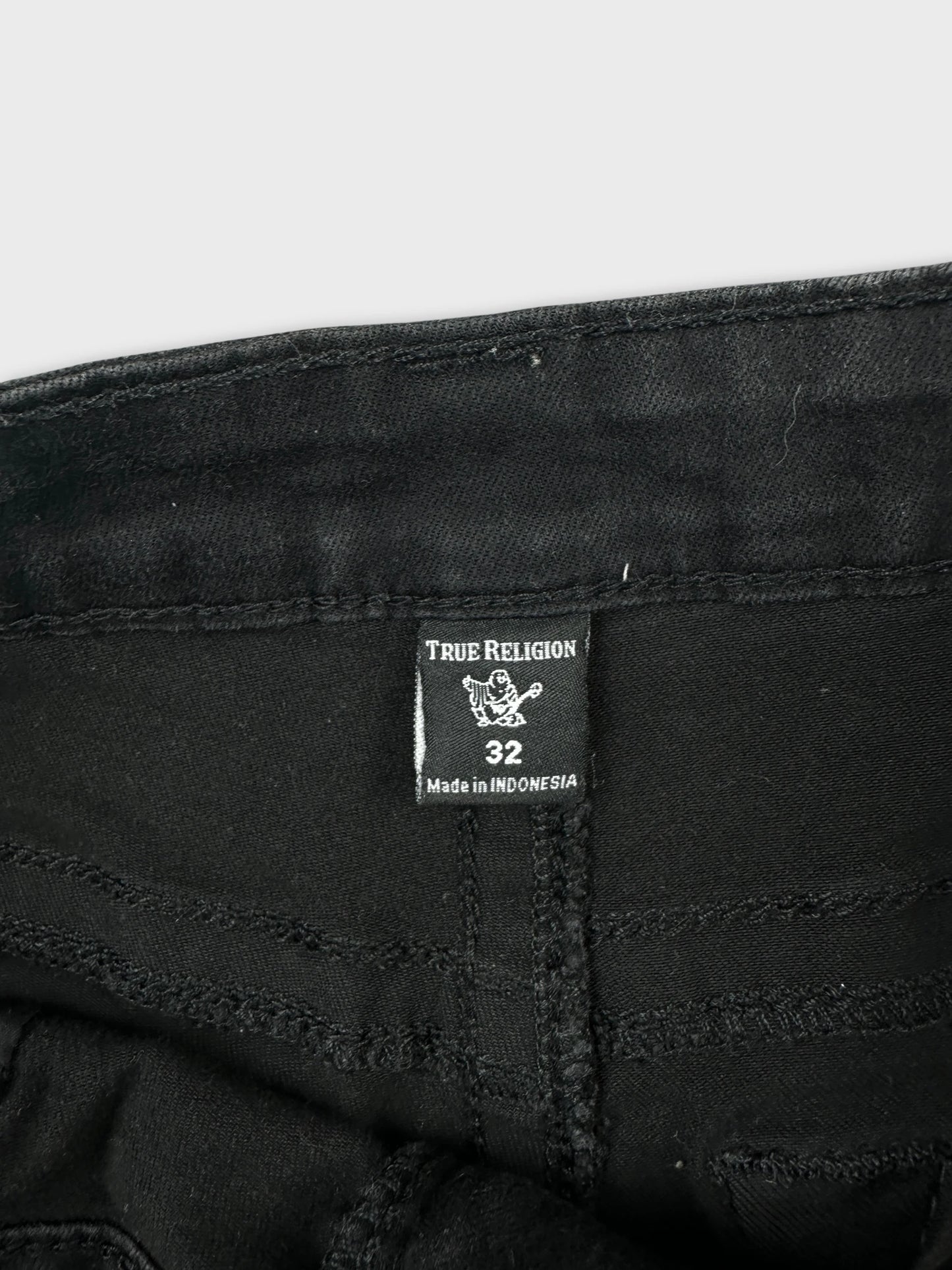 Detail view of black denim shorts featuring visible stitching and label.