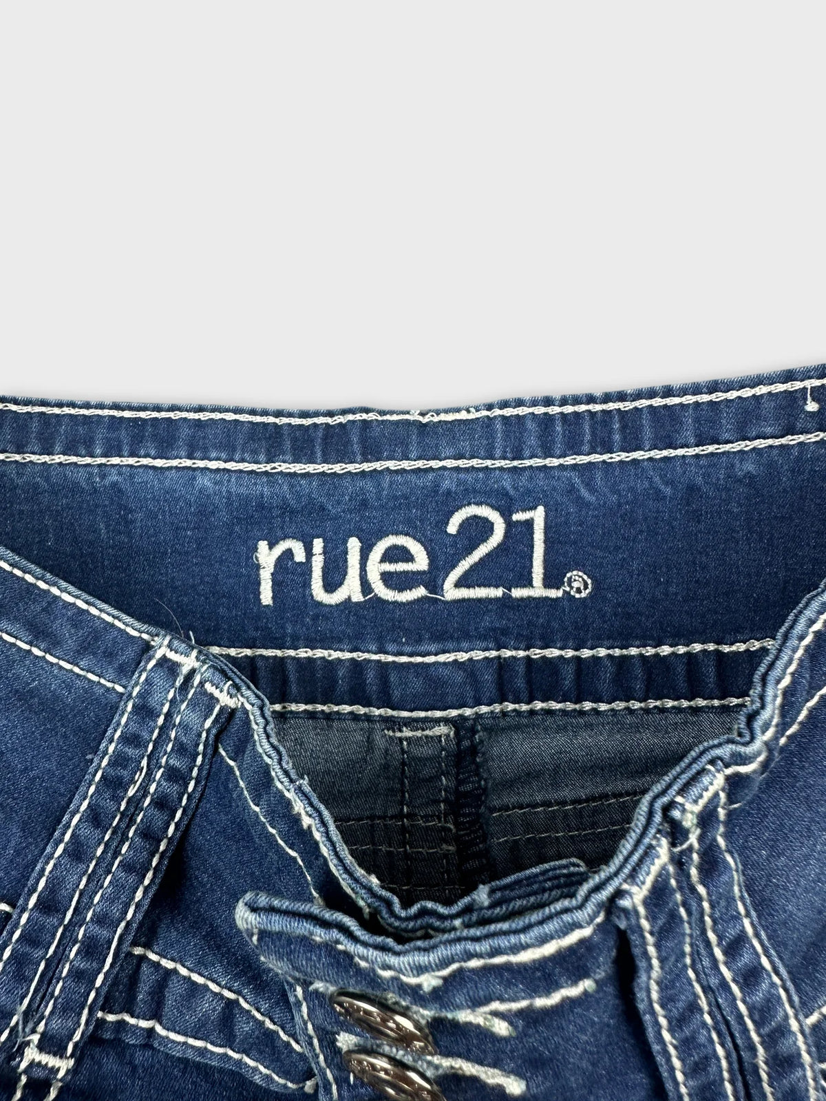 Detail view of women's denim shorts in dark blue with visible stitching and brand logo.