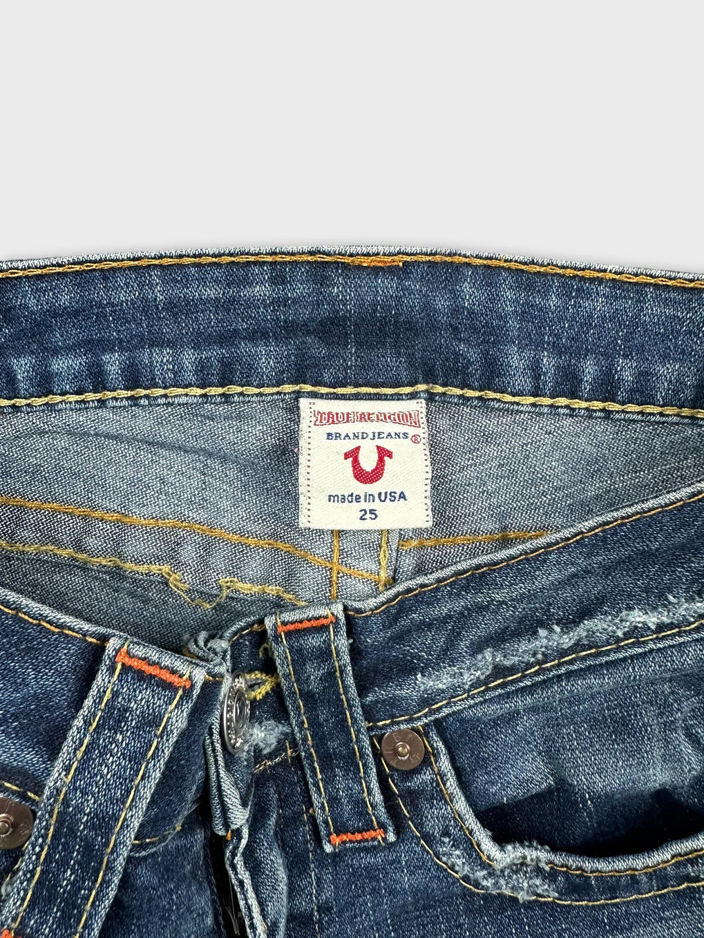 Detail view of women denim shorts in blue with orange stitching.