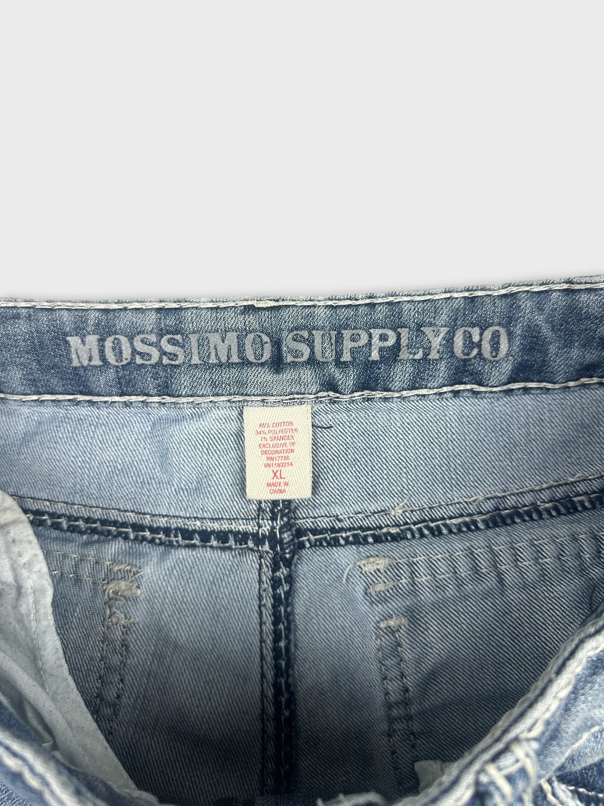 Detail view of denim shorts showing light blue color and brand tag.