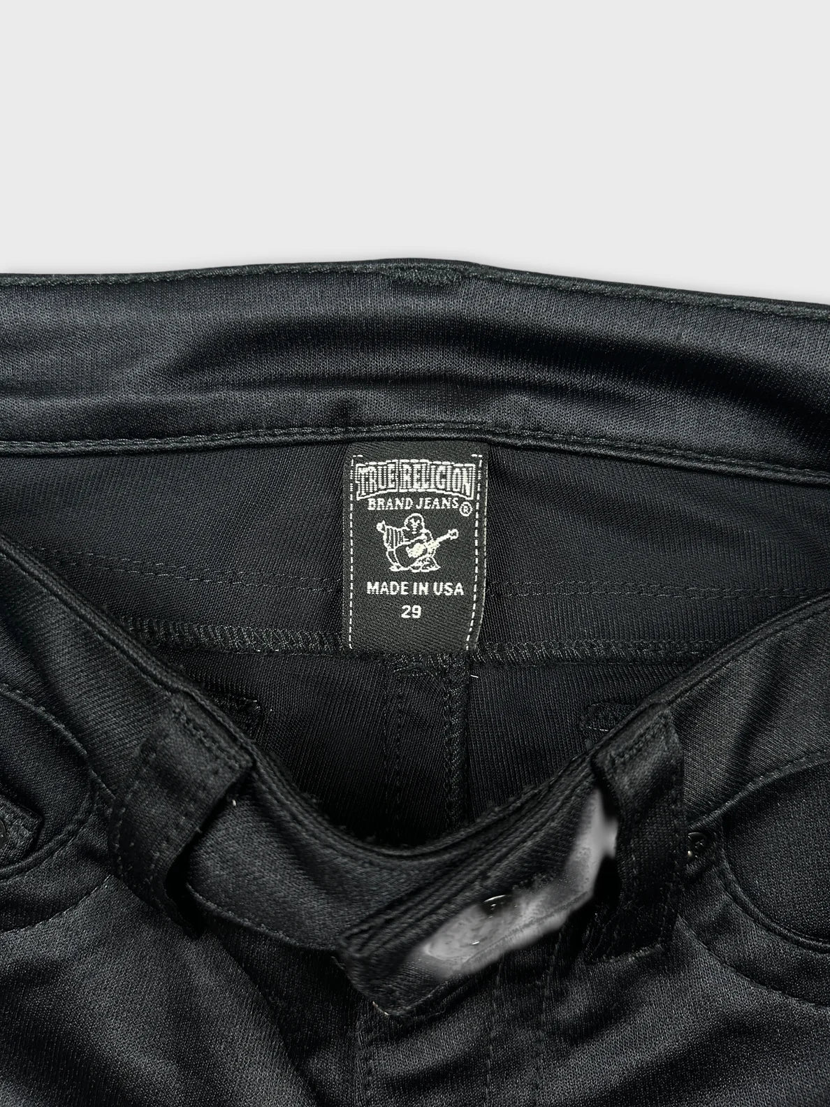 Detail view of black denim shorts with brand tag visible.