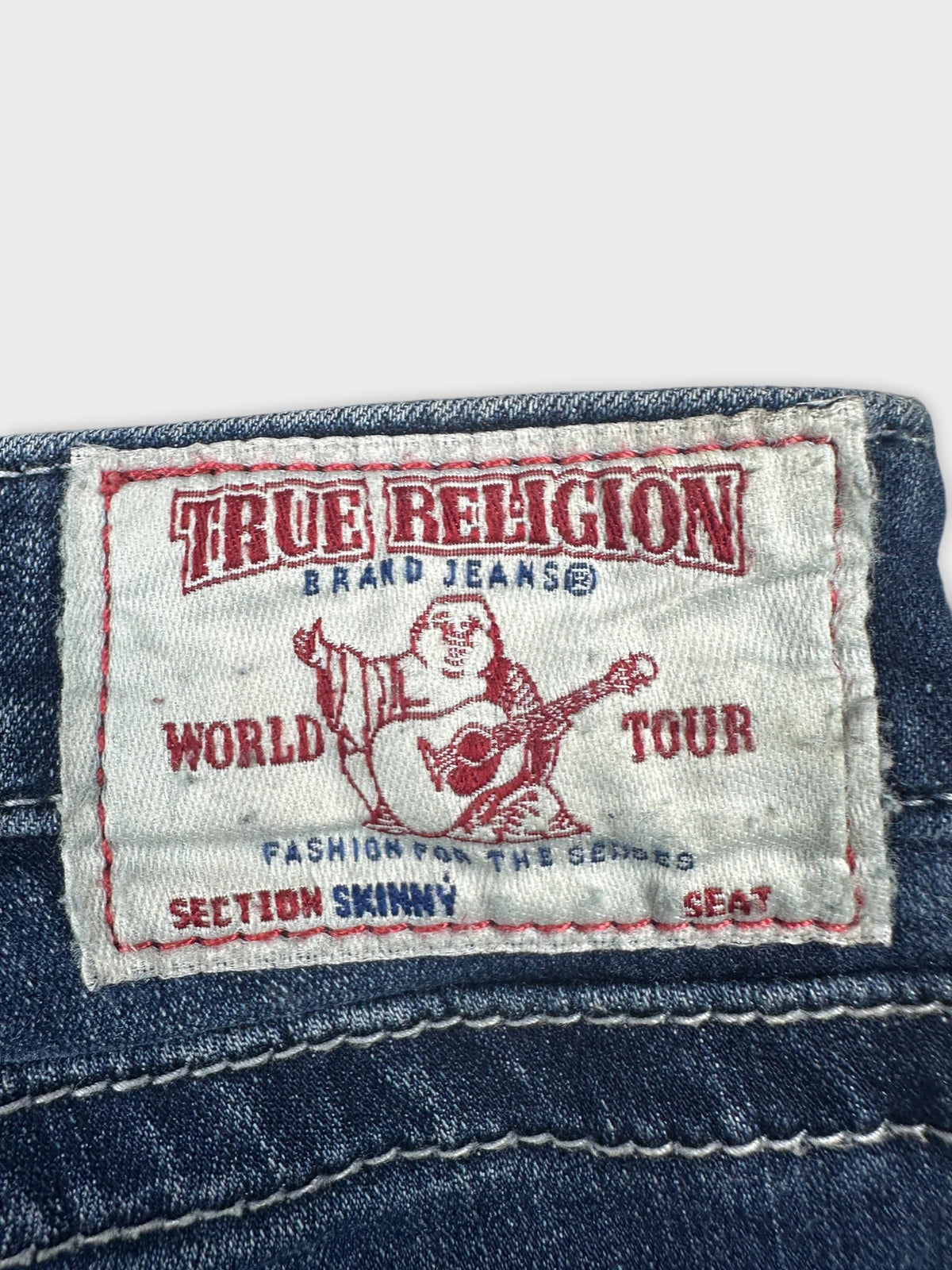 Detail view of women denim shorts showing True Religion label and stitching.