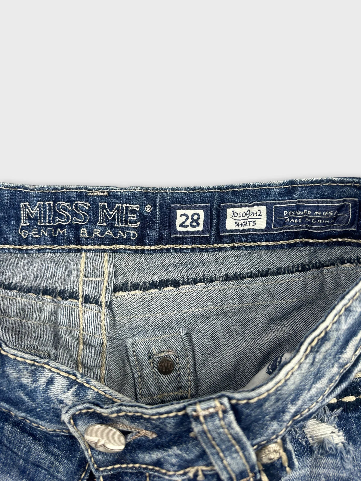 Detail view of blue denim shorts featuring a branded waistband and stitching.