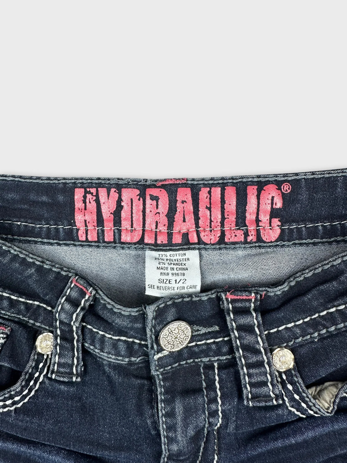 Detail view of women denim shorts featuring dark wash and decorative buttons.