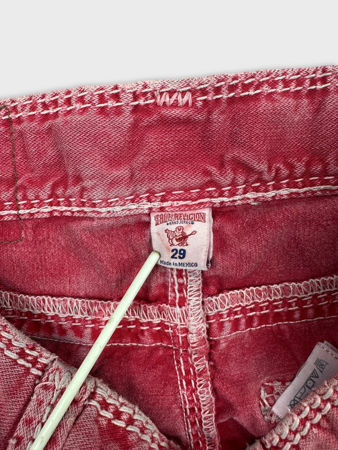 Detail view of pink denim shorts showcasing vibrant stitching and tag.