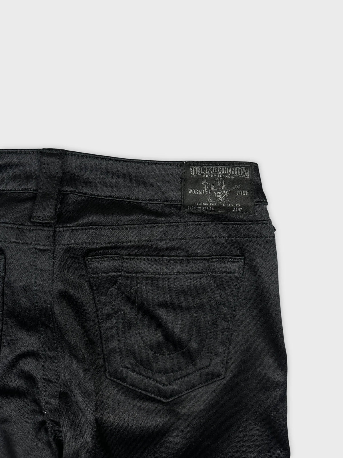 Detail view of black denim shorts featuring intricate back pocket stitching.