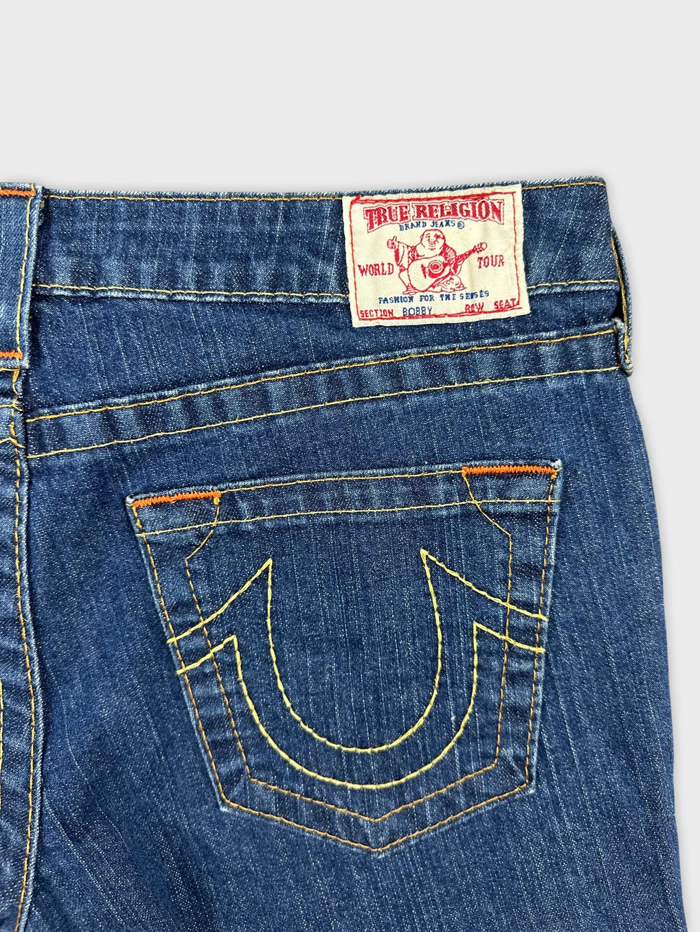 Detail view of women's denim shorts showing dark blue color and embroidered back pocket.