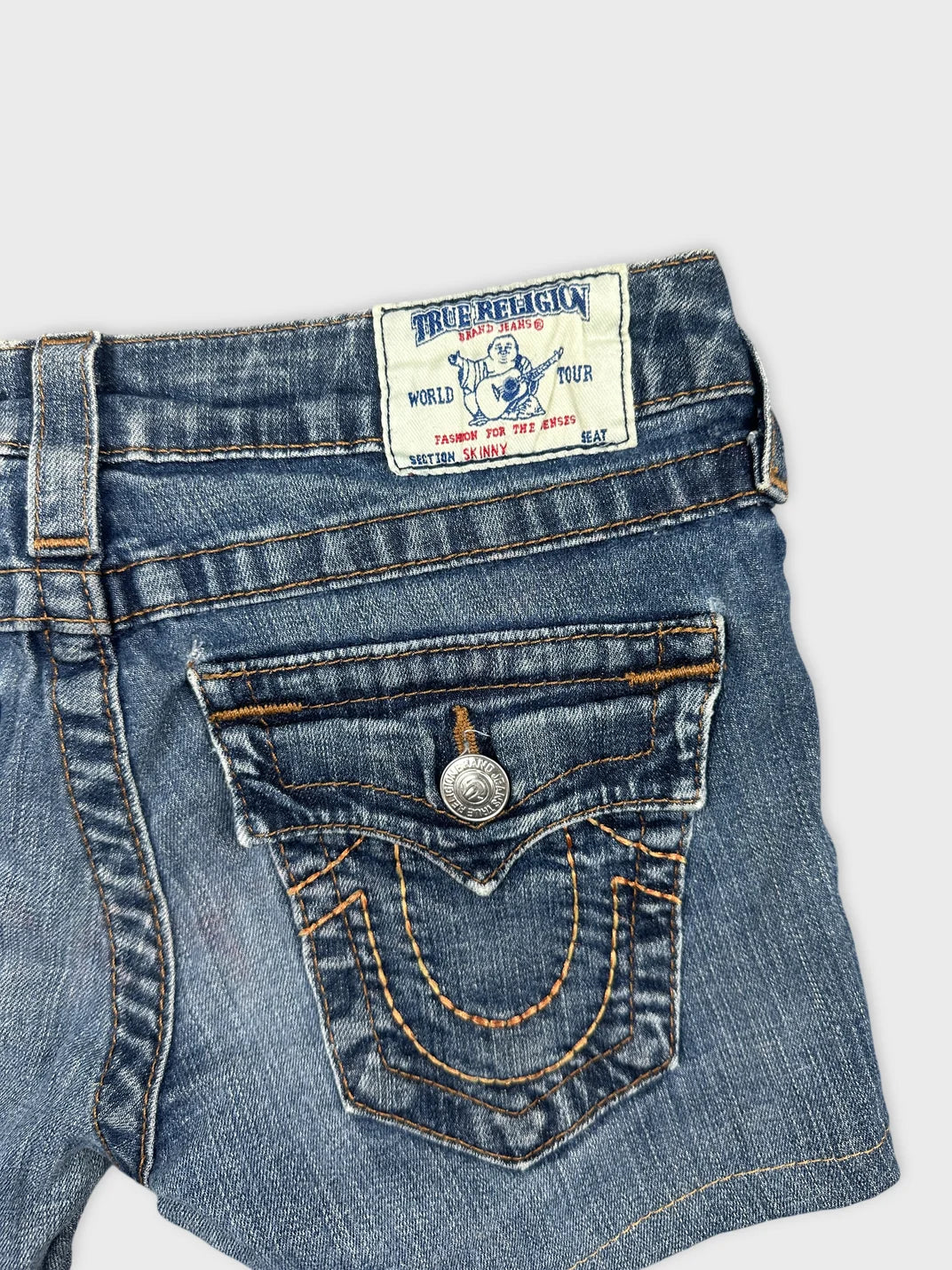 Detail view of women denim shorts featuring blue fabric and embroidered back pockets.
