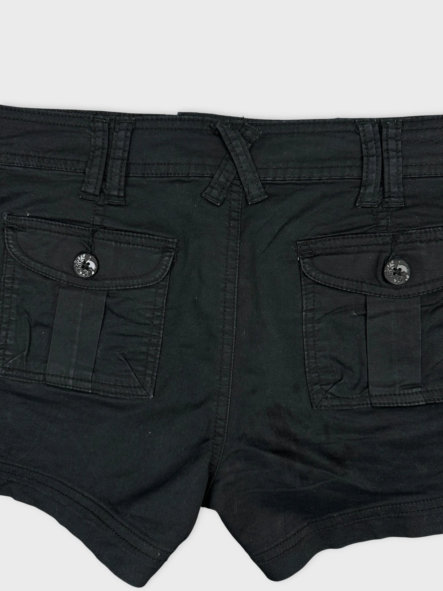 Detail view of black denim shorts with pockets and button details.