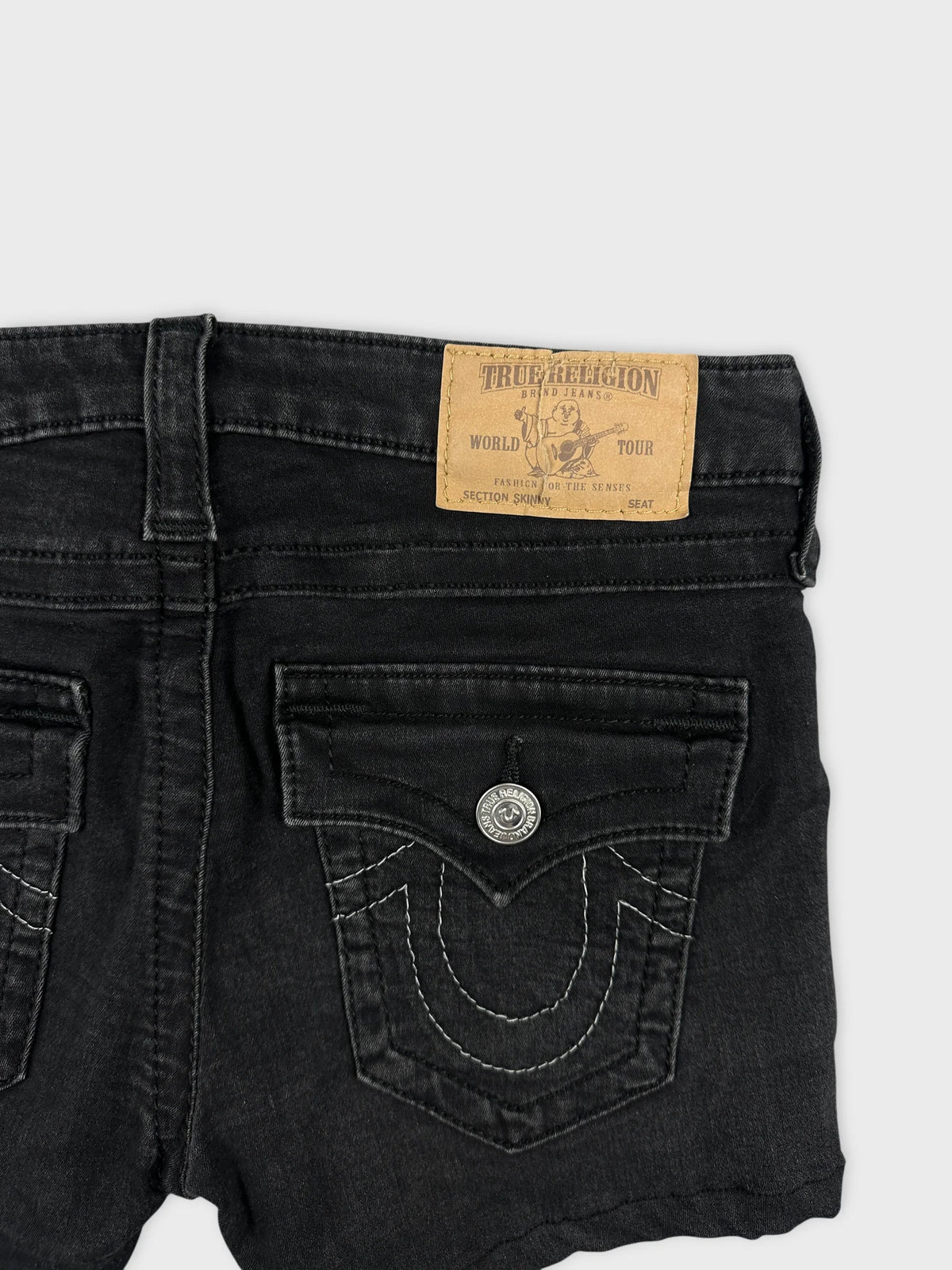 Detail view of black denim shorts featuring back pocket stitching design.
