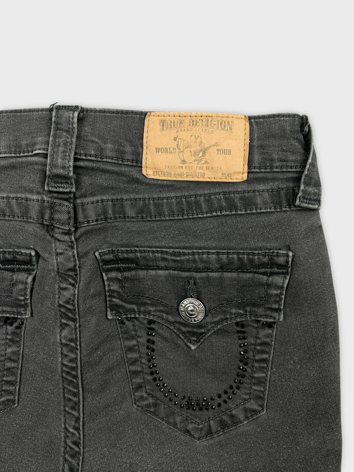 Detail view of black denim shorts featuring decorative back pockets.