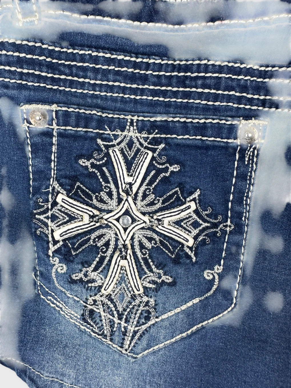 Detail view of women denim shorts featuring embroidered design in blue.