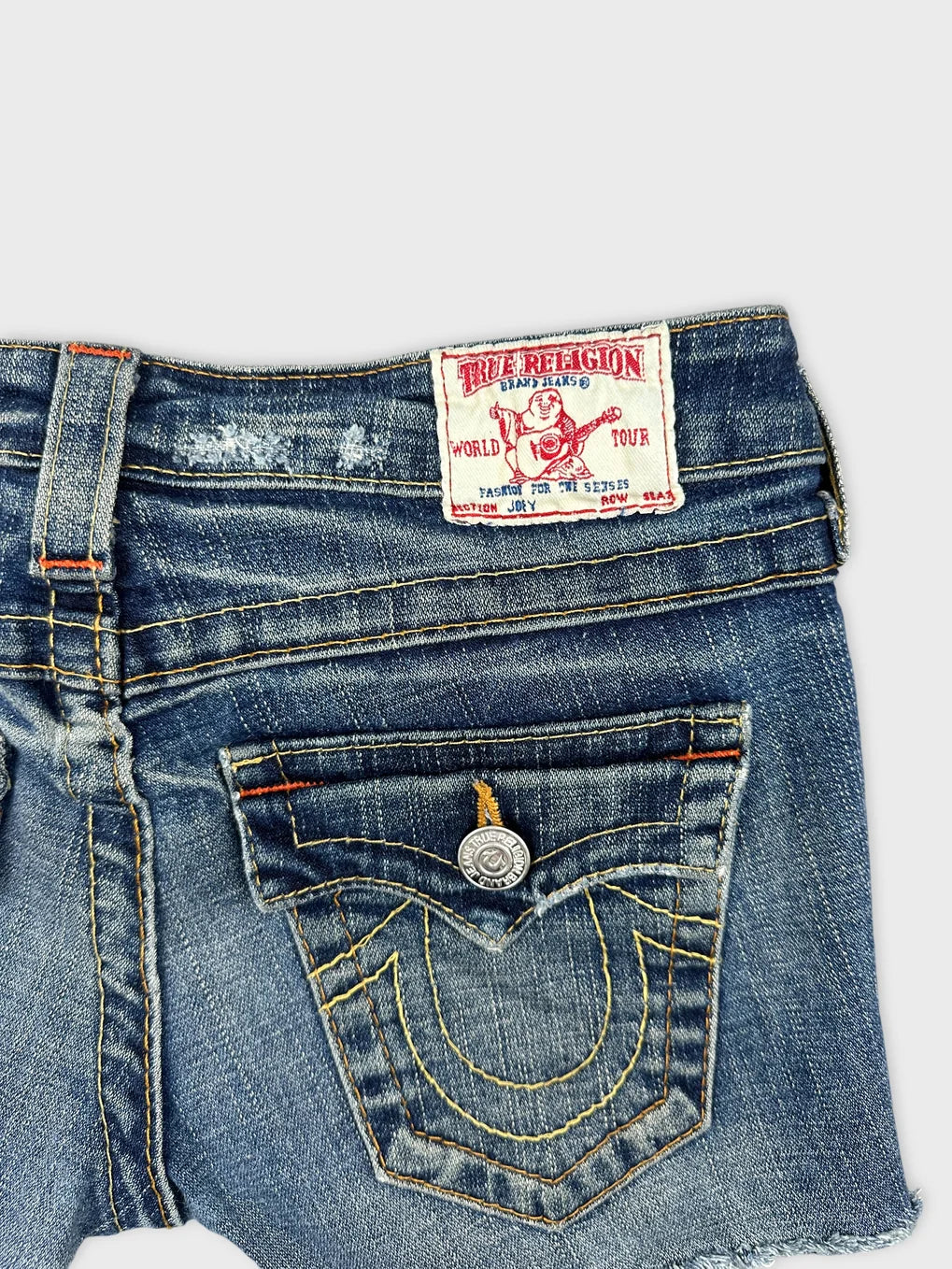 Detail view of blue denim shorts featuring stitched back pocket design.