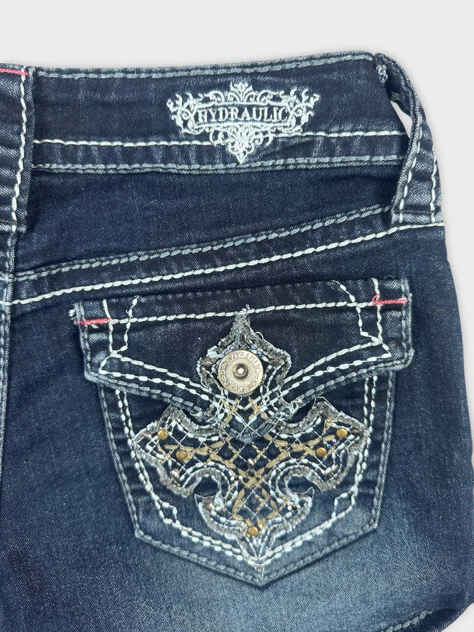 Detail view of women's denim shorts featuring a dark blue color and embroidered embellishment.