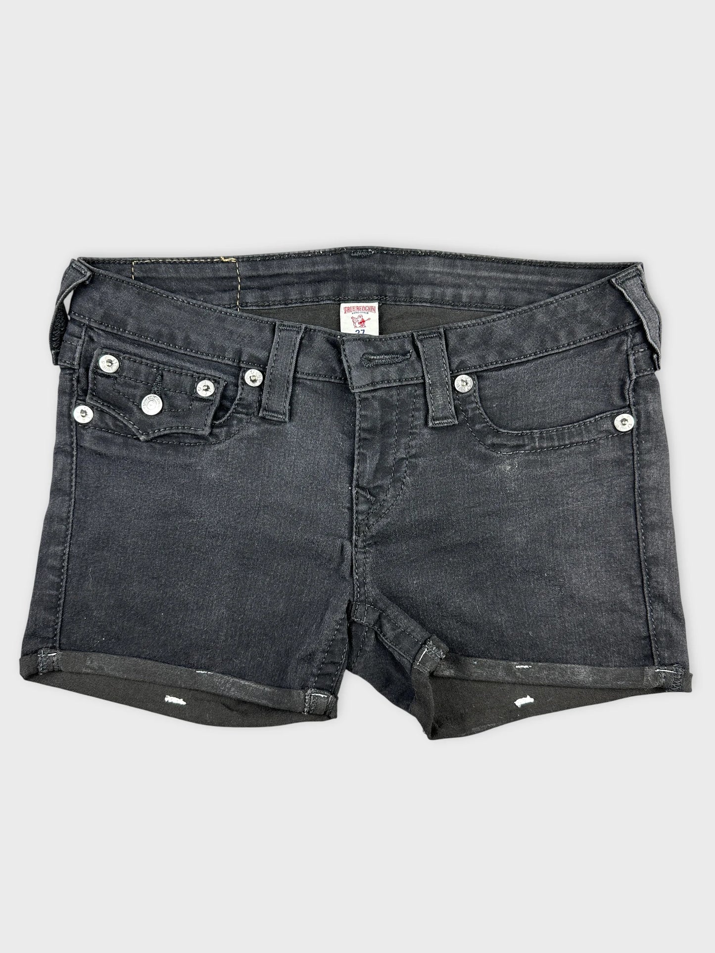 Front view of black denim shorts featuring a rolled hem and silver buttons.