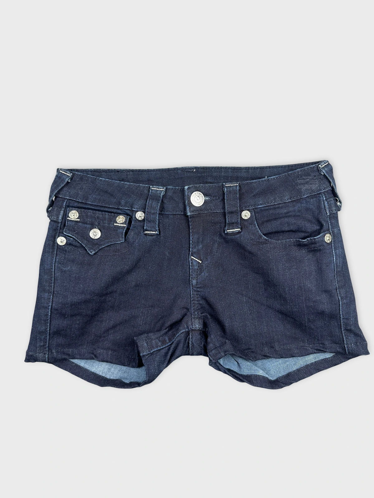 Front view of dark blue denim shorts with silver button details.