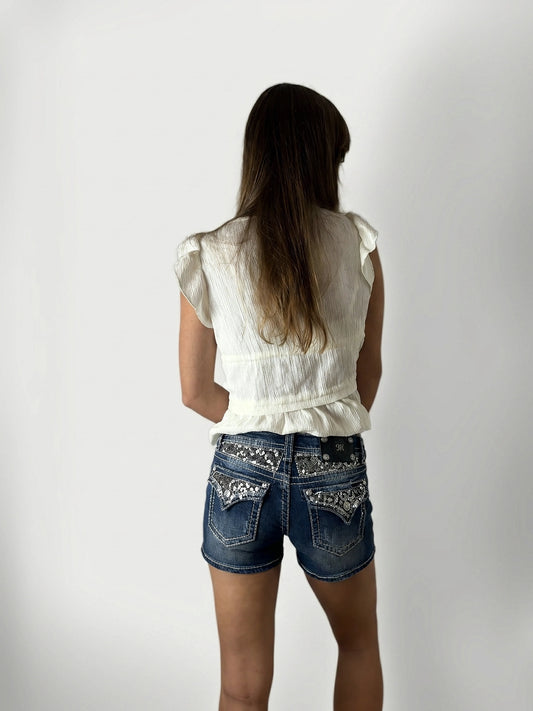 Back view of women's denim shorts in dark blue with embellished pockets.