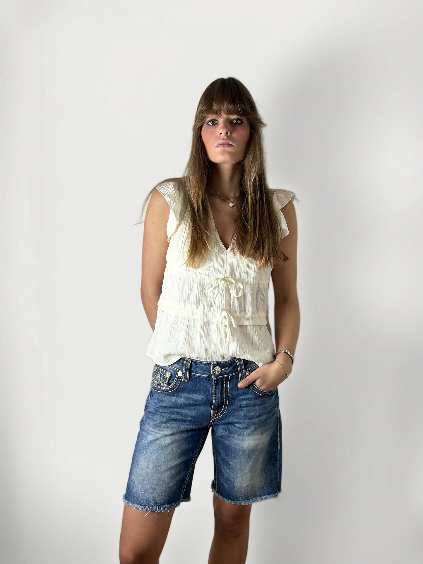 Front view of women's denim shorts in blue with frayed hem.