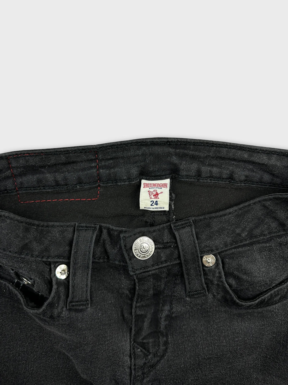 Detail view of a black denim skirt showcasing the button and stitching.