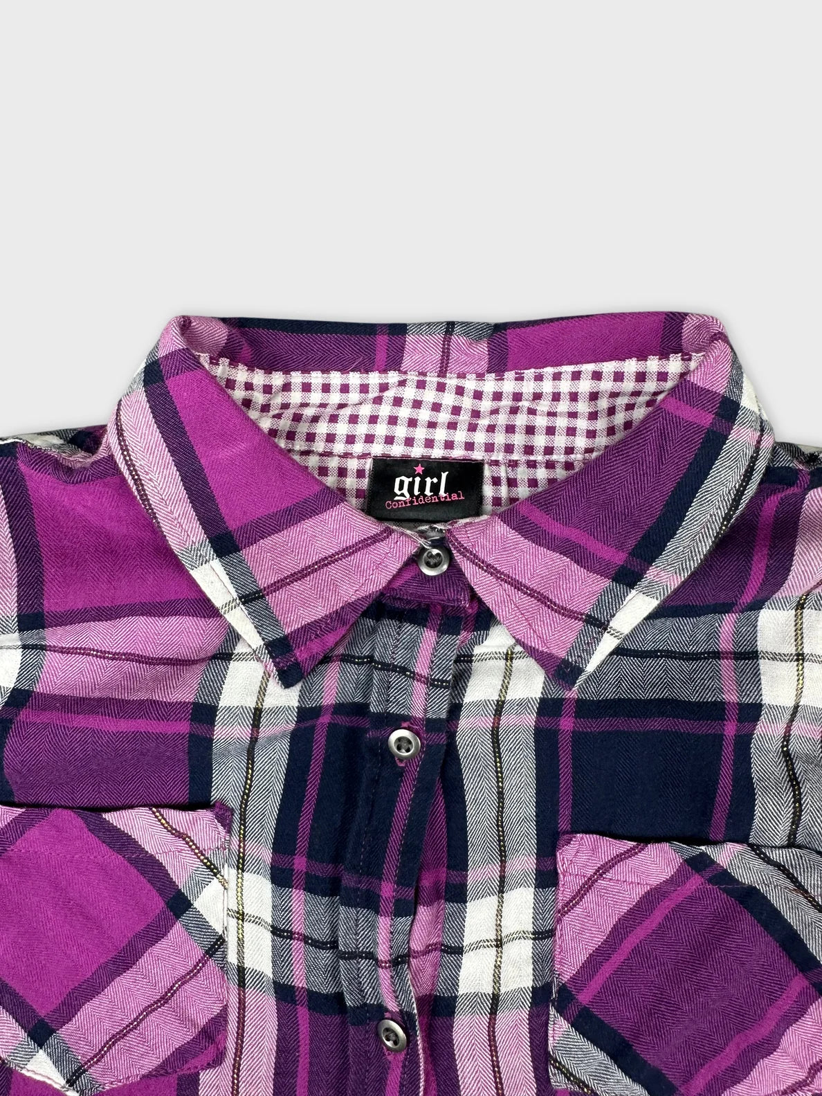 Detail view of a women's long sleeve shirt in purple plaid pattern.