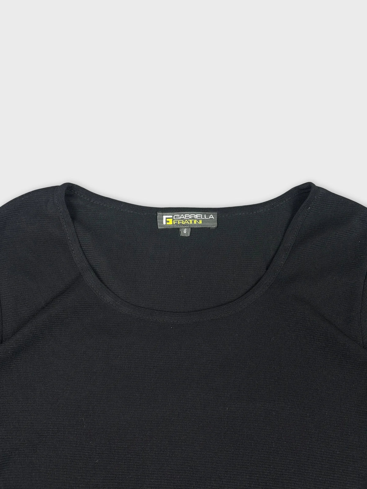 Detail view of a black long sleeve shirt with a scoop neckline.