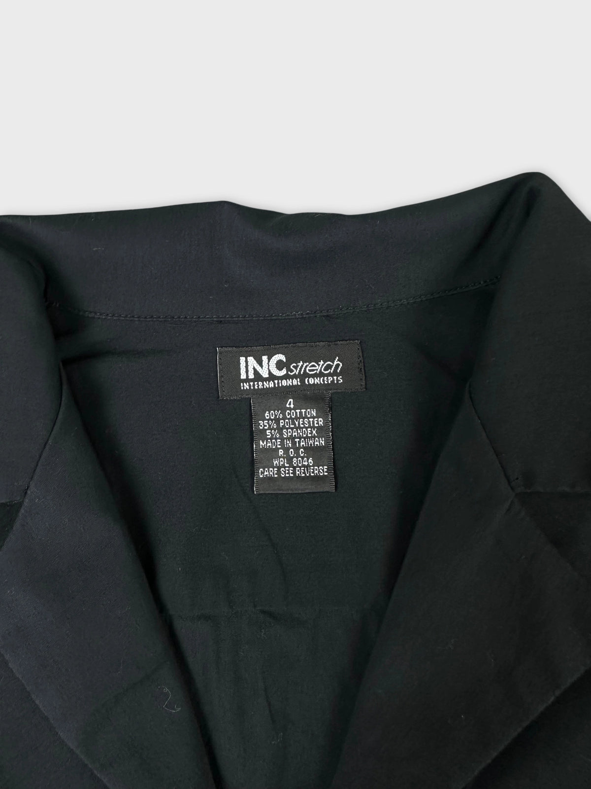 Detail view of a black long sleeve shirt with collar and care tag.