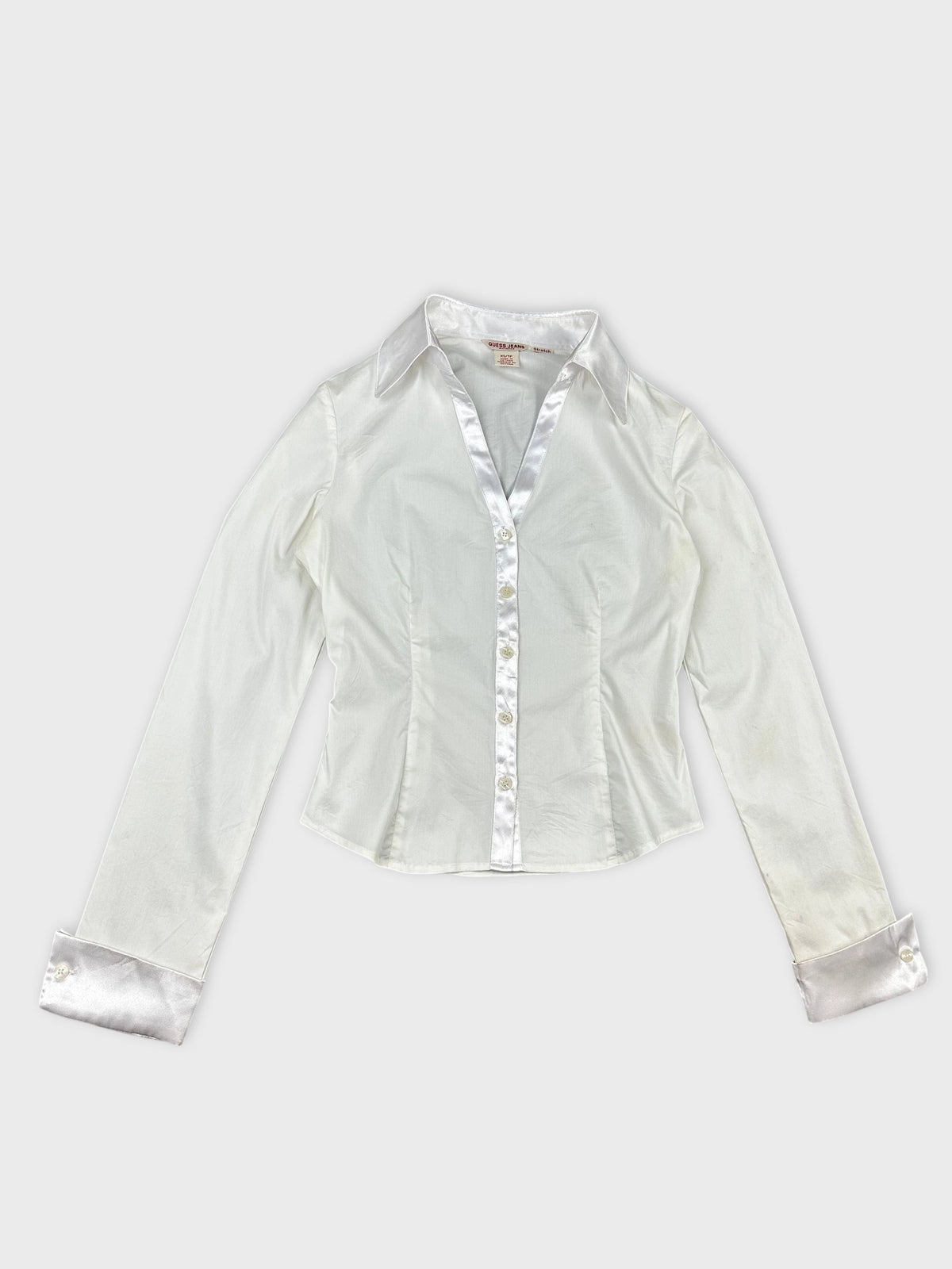 Detail view of a white long sleeve shirt with satin trim.
