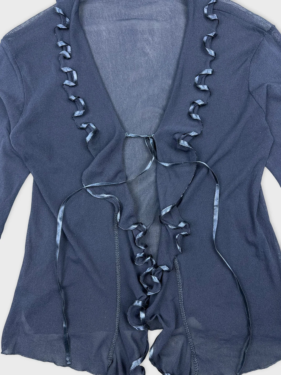 Detail view of a long sleeve shirt in navy blue with ruffled ribbon trim.