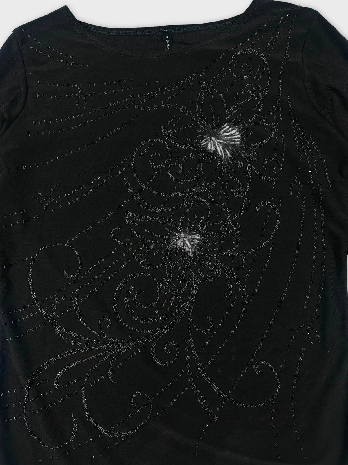 Detail view of a black long sleeve shirt with floral embellishments.