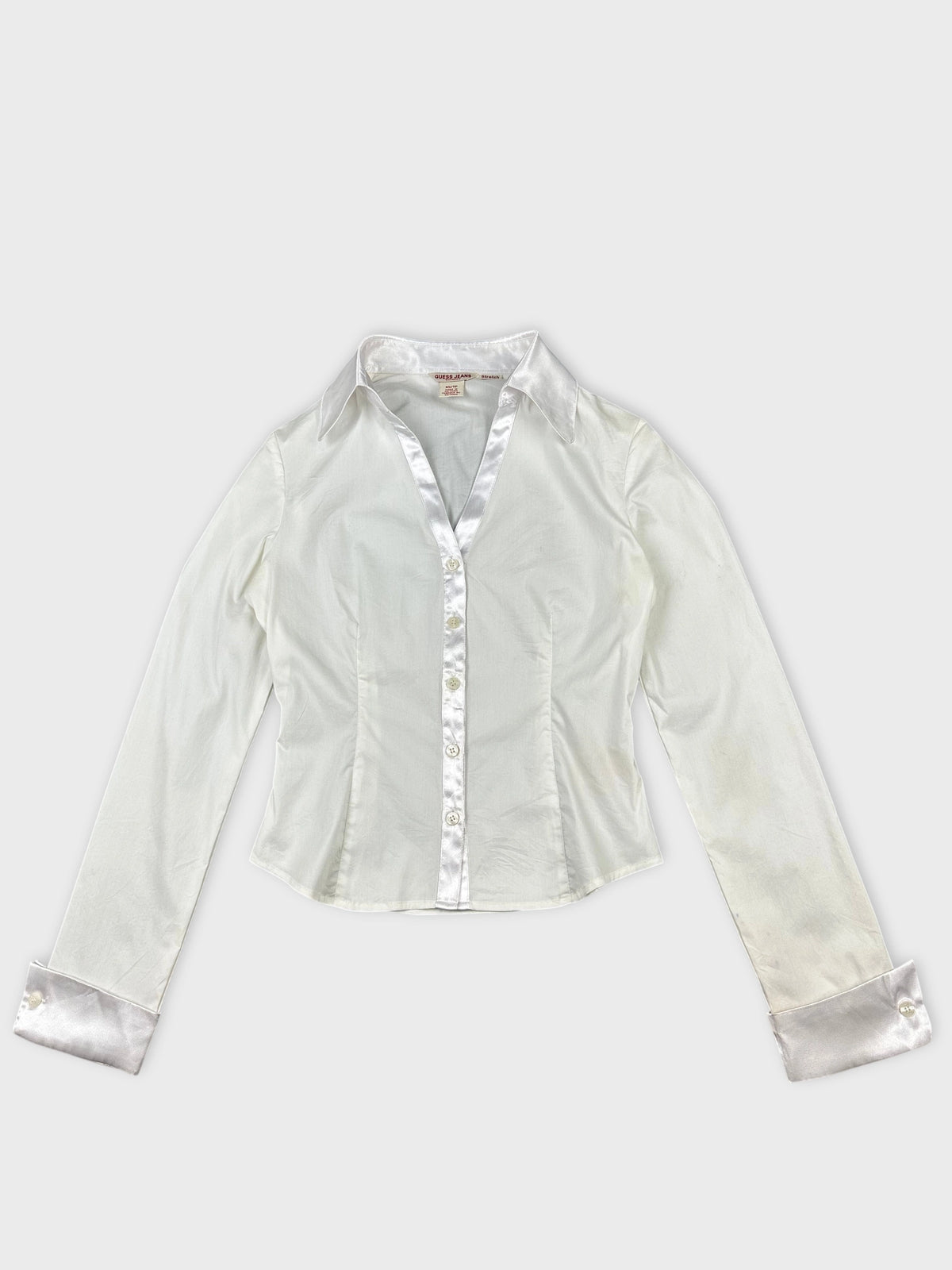 Front view of a white long sleeve shirt with satin trim and buttons.