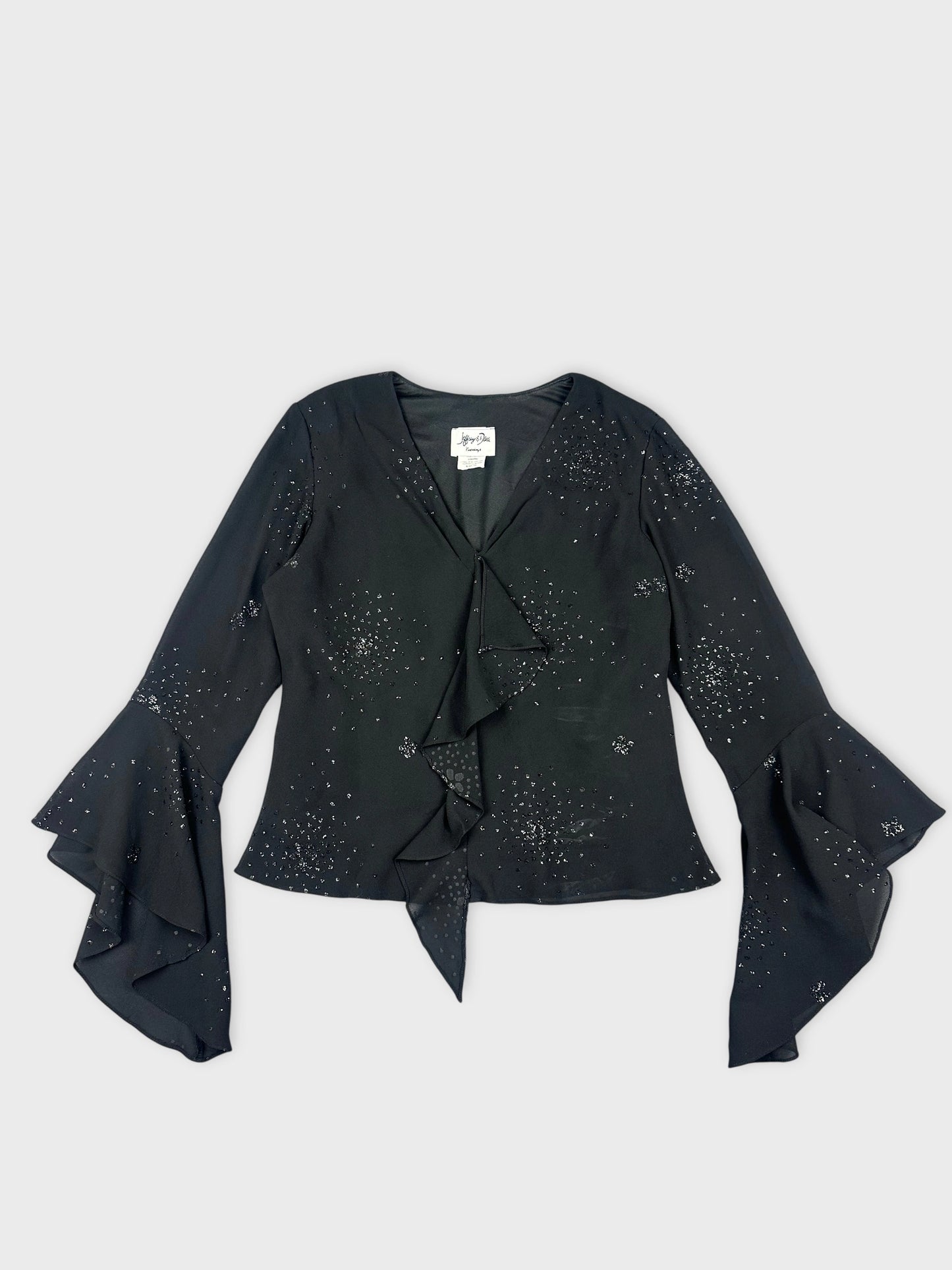 Front view of a black long sleeve shirt with ruffled hem and sparkly details.