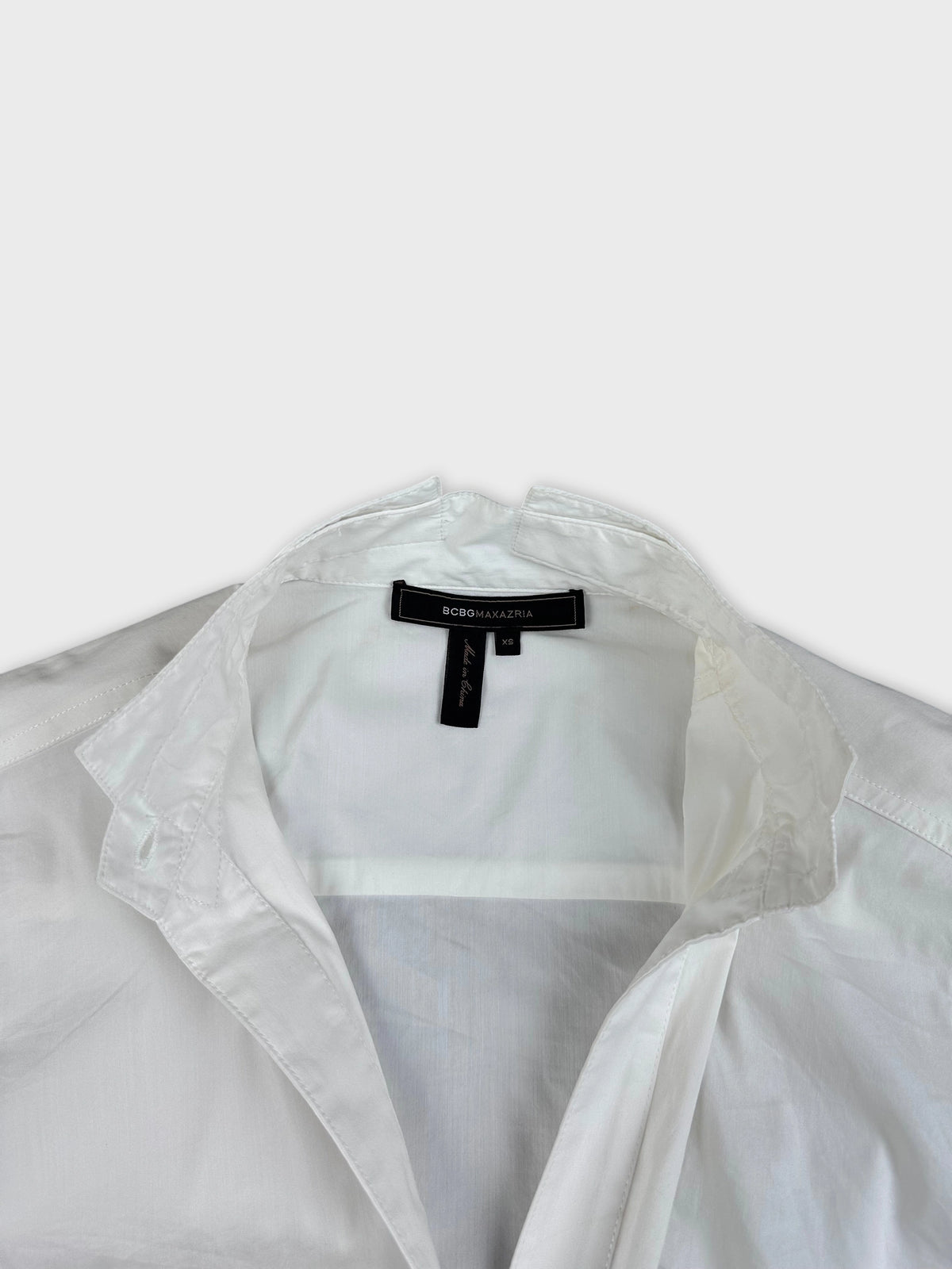 Detail view of a white long sleeve top with a pointed collar